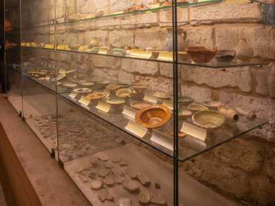 Una parte degli oggetti rinvenuti in queste sepolture e in quelle delle confraternite viste poco prima � conservata all�interno di apposite teche. Sono databili dal XII al XVI secolo: fibule, monete, piatti, lucerne